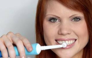 Девушка чистит зубы электрической щеткой