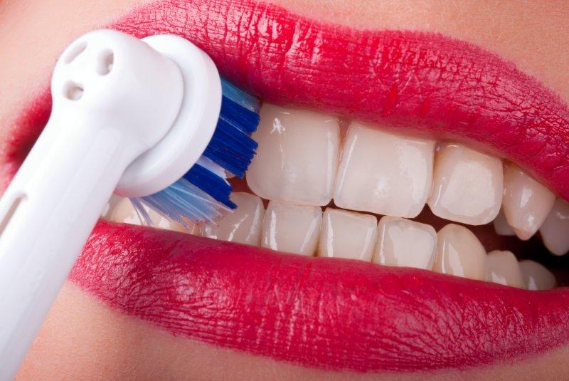 девушка чистит зубы электрической щеткой